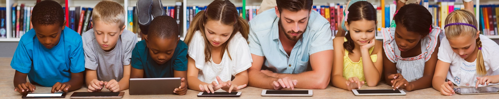 group of students and a teacher on the floor each with an ipad in the library